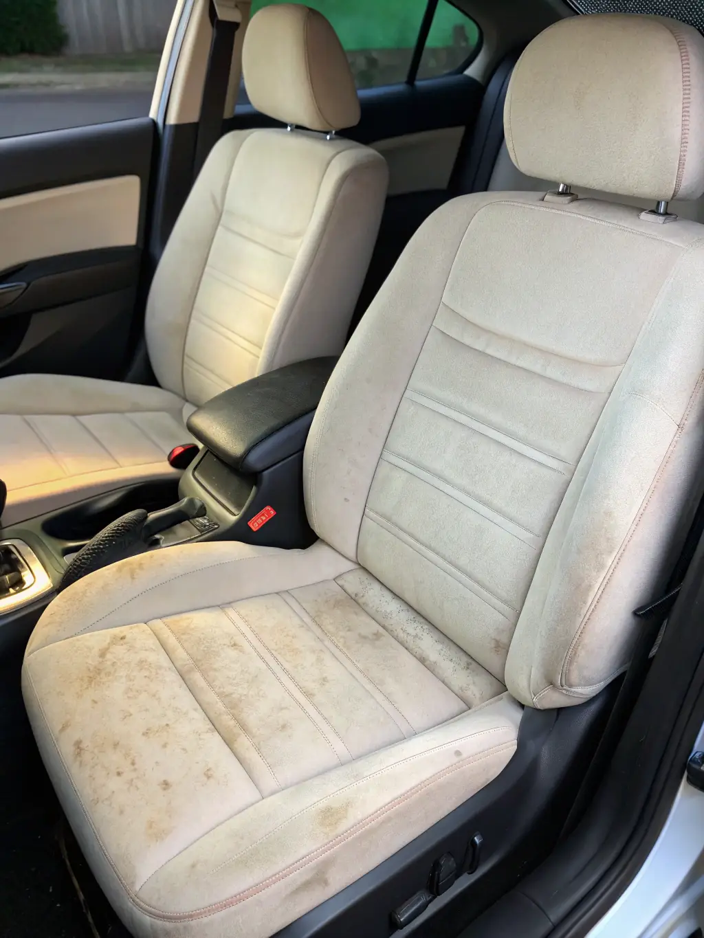 A before-and-after shot of a heavily stained car seat, showcasing the effectiveness of Jonesy's upholstery cleaning service.